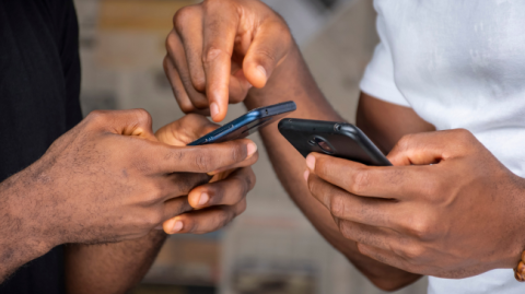 Mobile phones changing the information dissemination landscape Two African men holding mobile phones