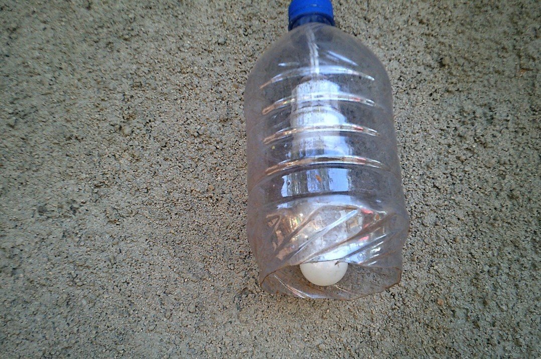 A single lightbulb enclosed in a simple, rain‑protective cover made from a recycled 2 litre plastic bottle with the wire going out through a hole in the lid, with the bottom of the bottle cut off.