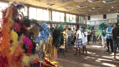 People in brightly coloured feathered costumes, preparing for the carnival