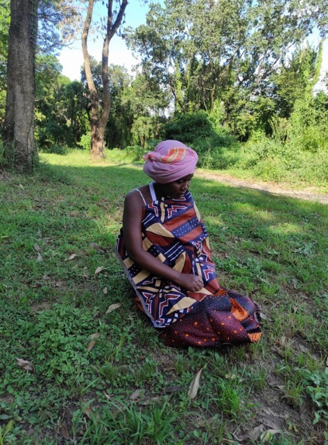 A woman sitting on the grass in her colourful traditional clothing